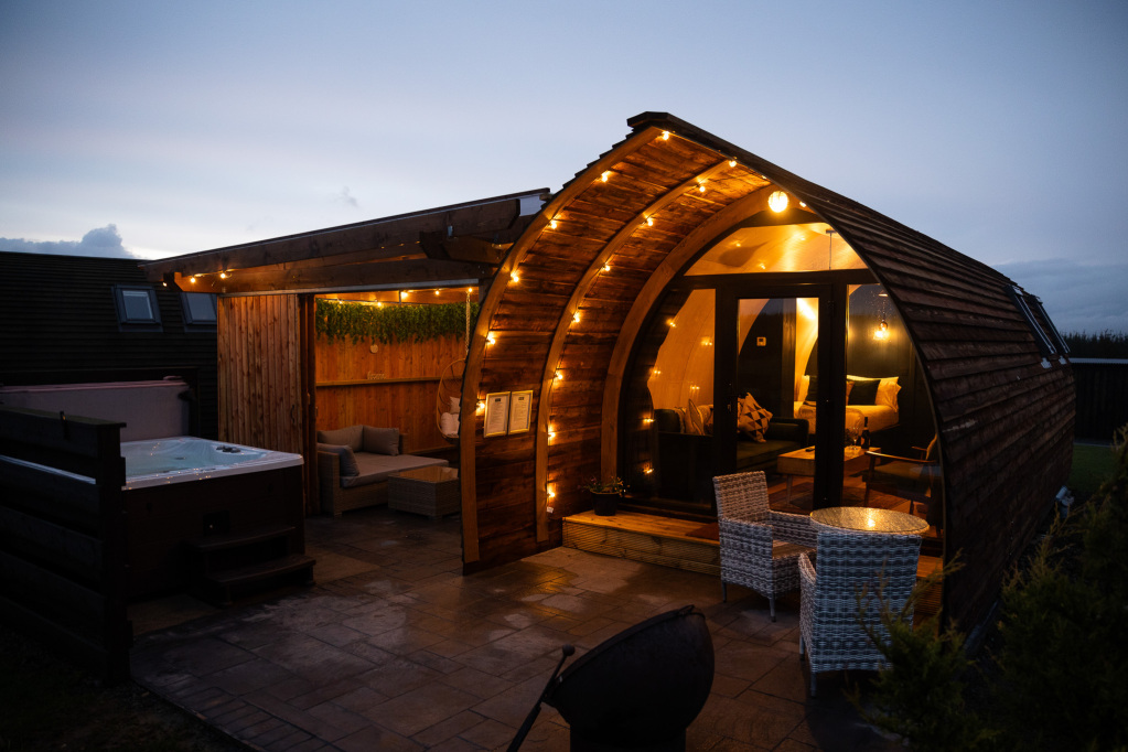 Arched timber Premium Pod at dusk with private hot tub